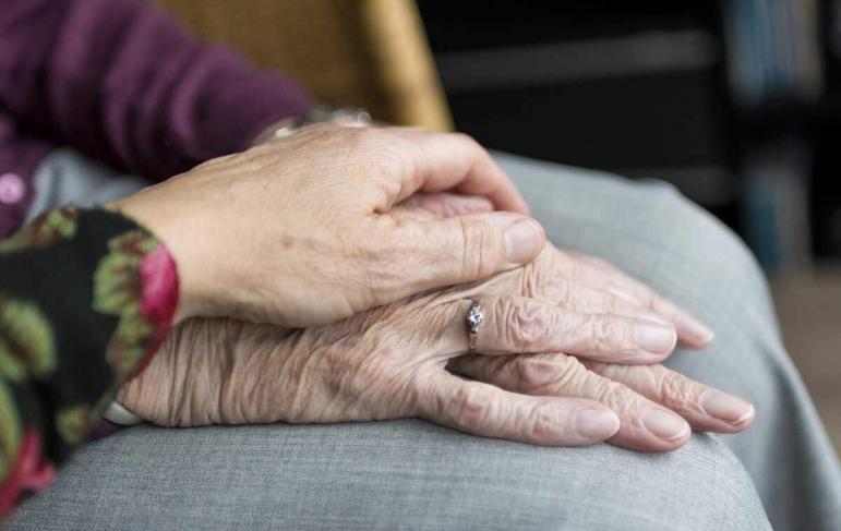 Younger adult hand on a pair of elderly hands