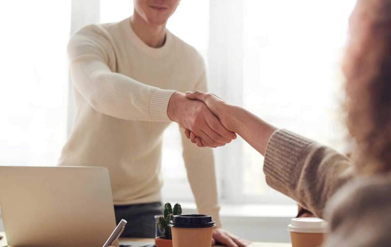 2 people shaking hands across a desk